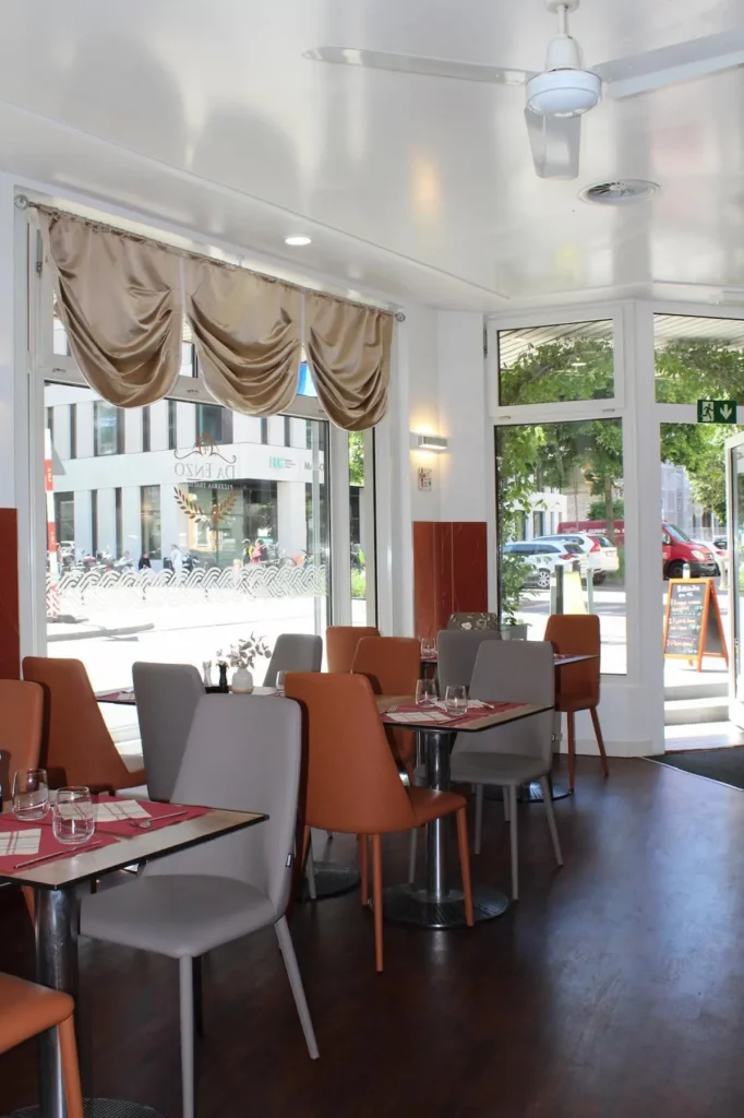 Salle lumineuse du restaurant Da Enzo à Genève avec tables dressées et ambiance italienne.
